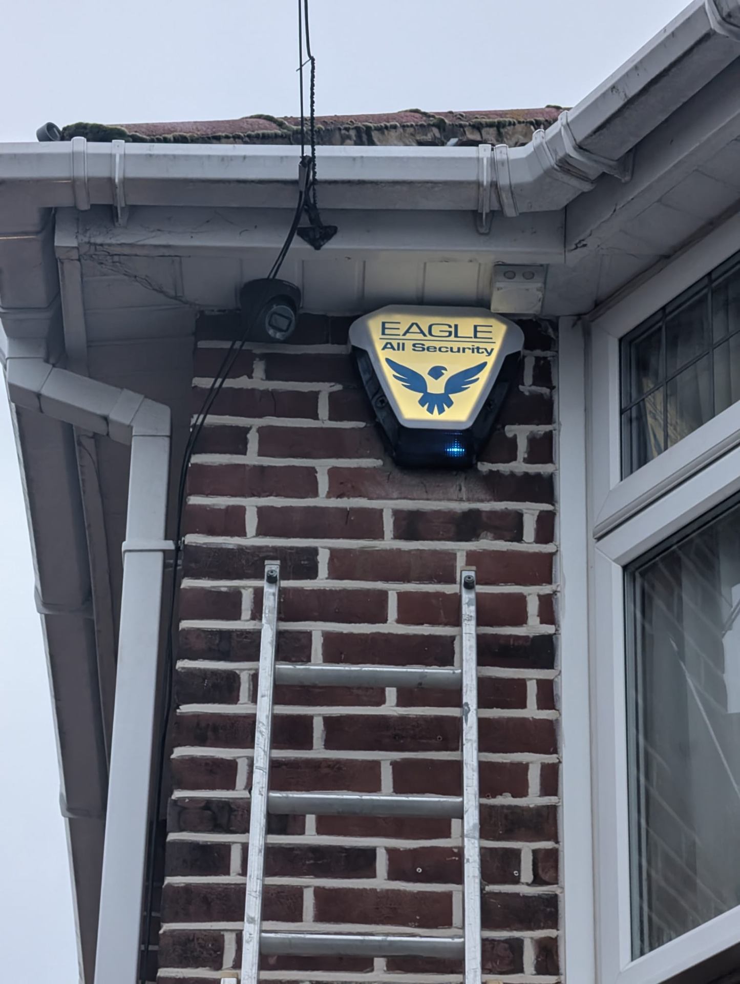 Security engineer on ladder installing upgraded CCTV camera